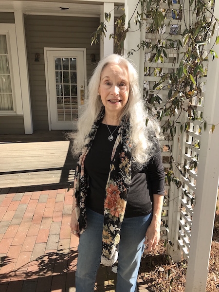 Louise Hawes ’65 standing in front of her home.
